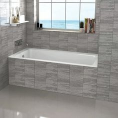 a bath tub sitting under a window next to a shelf with books on top of it