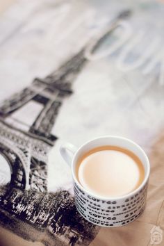 a cup of coffee sitting next to the eiffel tower