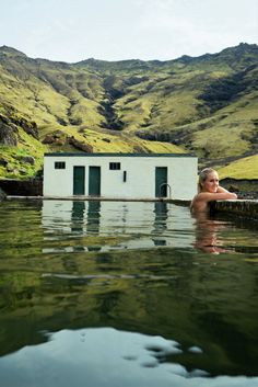 a woman is in the water near a small house with a shed on it's side