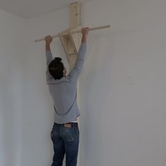 a man is working on the ceiling in his room with no one around him or someone else