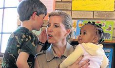 an older woman is holding a child in her lap and talking to another young boy