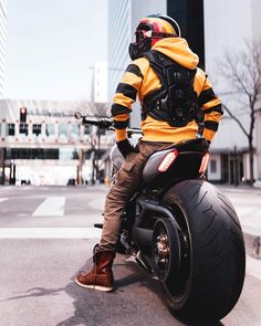 a man sitting on top of a motorcycle wearing a helmet and goggles, in the city