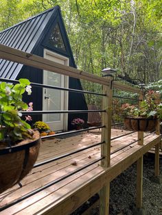 a wooden deck with potted plants on it next to a small cabin in the woods