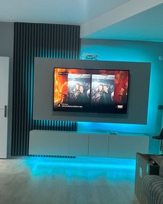 a living room with two televisions mounted on the wall and blue lights in the floor