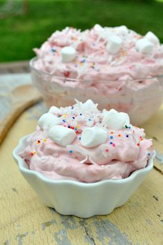 two bowls filled with pink and white frosted food on top of a wooden table