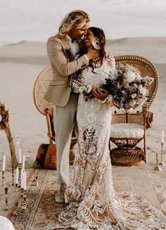 a bride and groom standing in front of a desert setting with candles on the ground