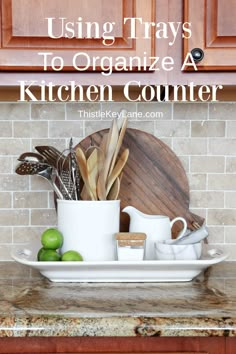 a kitchen counter with white dishes and wooden cutting boards on it that says using trays to organize a kitchen counter