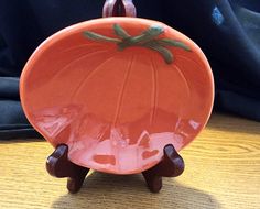 an orange plate sitting on top of a wooden table next to a blue cloth bag