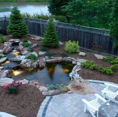 a small pond in the middle of a patio with chairs around it and lights on