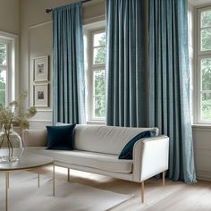 a living room filled with furniture and large windows covered in blue curtained drapes