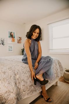 a woman sitting on top of a bed with her legs hanging off the bed frame