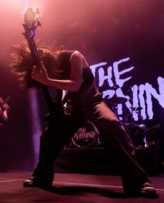 a woman with long hair holding a guitar in front of her face and performing on stage