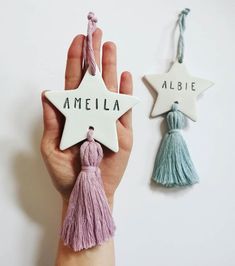 a hand holding a ceramic star ornament with tassels