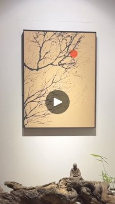 an art piece hanging on the wall next to a tree branch with a red ball in it