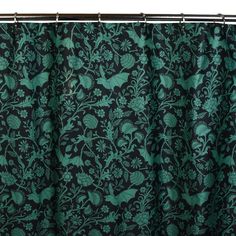 a black and green shower curtain with floral designs on the bottom, in front of a white background