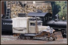 an old truck is sitting on the tracks next to a model train and other toy cars