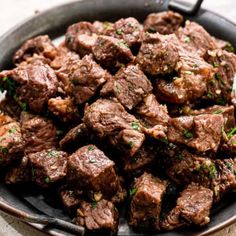 a skillet filled with meat and garnished with parsley on the side