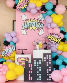 a party with balloons and decorations in the shape of cityscapes, buildings, and super hero signs