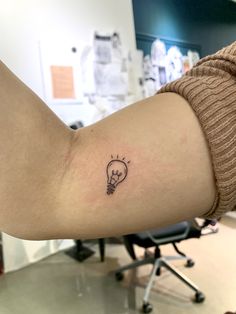 a small light bulb tattoo on the arm