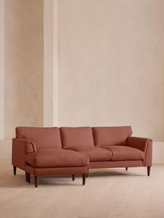 an orange couch sitting on top of a hard wood floor next to a white wall