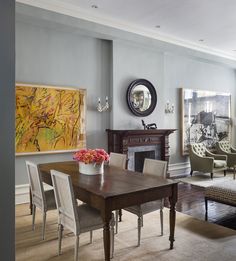 a dining room table with chairs around it and an art piece on the wall behind it