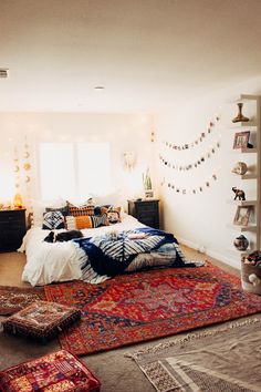 a bed room with a neatly made bed and lots of rugs on the floor