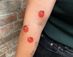 a woman's arm with three small tomatoes on the left side of her arm