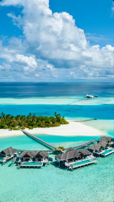 an aerial view of the water and beach in front of some huts with thatched roofs