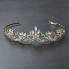 a gold tiara with crystal stones and leaves on the headband is seen in this image