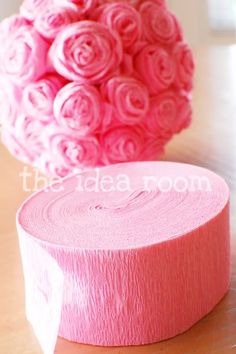 a roll of pink toilet paper sitting on top of a table next to a vase