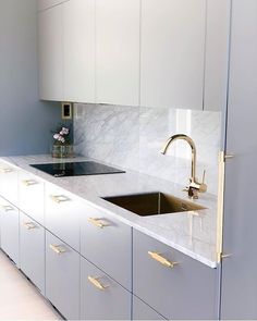 a kitchen with white cabinets and marble counter tops, gold faucet handles on the sink