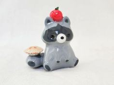 a small ceramic raccoon with a cherry on its head