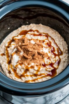 an oatmeal in a crock pot with caramel sauce and cinnamon on top