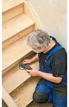 a man in overalls and safety glasses working on some stairs with a driller