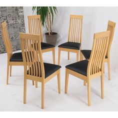 a group of wooden chairs sitting next to each other in front of a potted plant