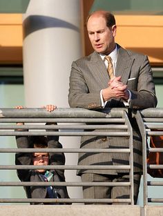 a man in a suit and tie standing next to a little boy on a balcony