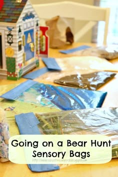 a table that has some bags on it and a toy house in the background with text overlay reading going on a bear hunt