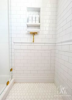 a white tiled bathroom with gold fixtures and yellow handles on the faucet in the shower