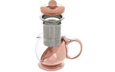 a pink coffee maker with a glass cup on it's side and a metal lid