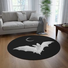 a living room with a white couch and a black bat rug on the wooden floor