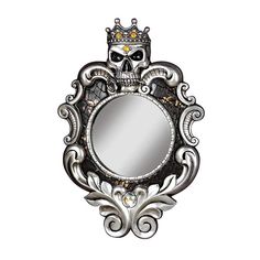 a mirror with a skull on it and a crown in the middle is hanging from a wall