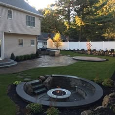 a backyard with a fire pit surrounded by landscaping