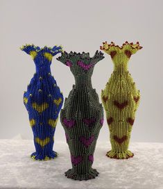 three vases made out of beads sitting on top of a snow covered ground,