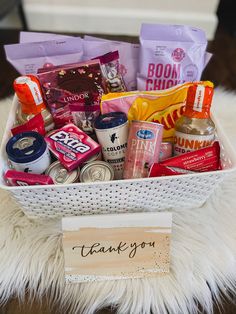 a white basket filled with lots of food on top of a furry floor next to a sign that says thank you