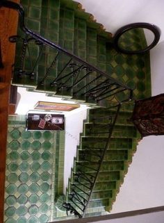 an overhead view of a spiral staircase with green tiles on the walls and below it