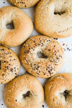 bagels with sesame seeds and poppy seed sprinkles on white parchment paper