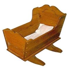 an old fashioned wooden baby crib with white sheets in it's bottom section