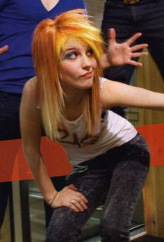 a woman with orange hair sitting on top of a stool