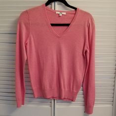 a pink sweater hanging on a white door