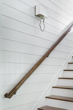 there is a wooden stair case on the wall next to the white walls and wood steps